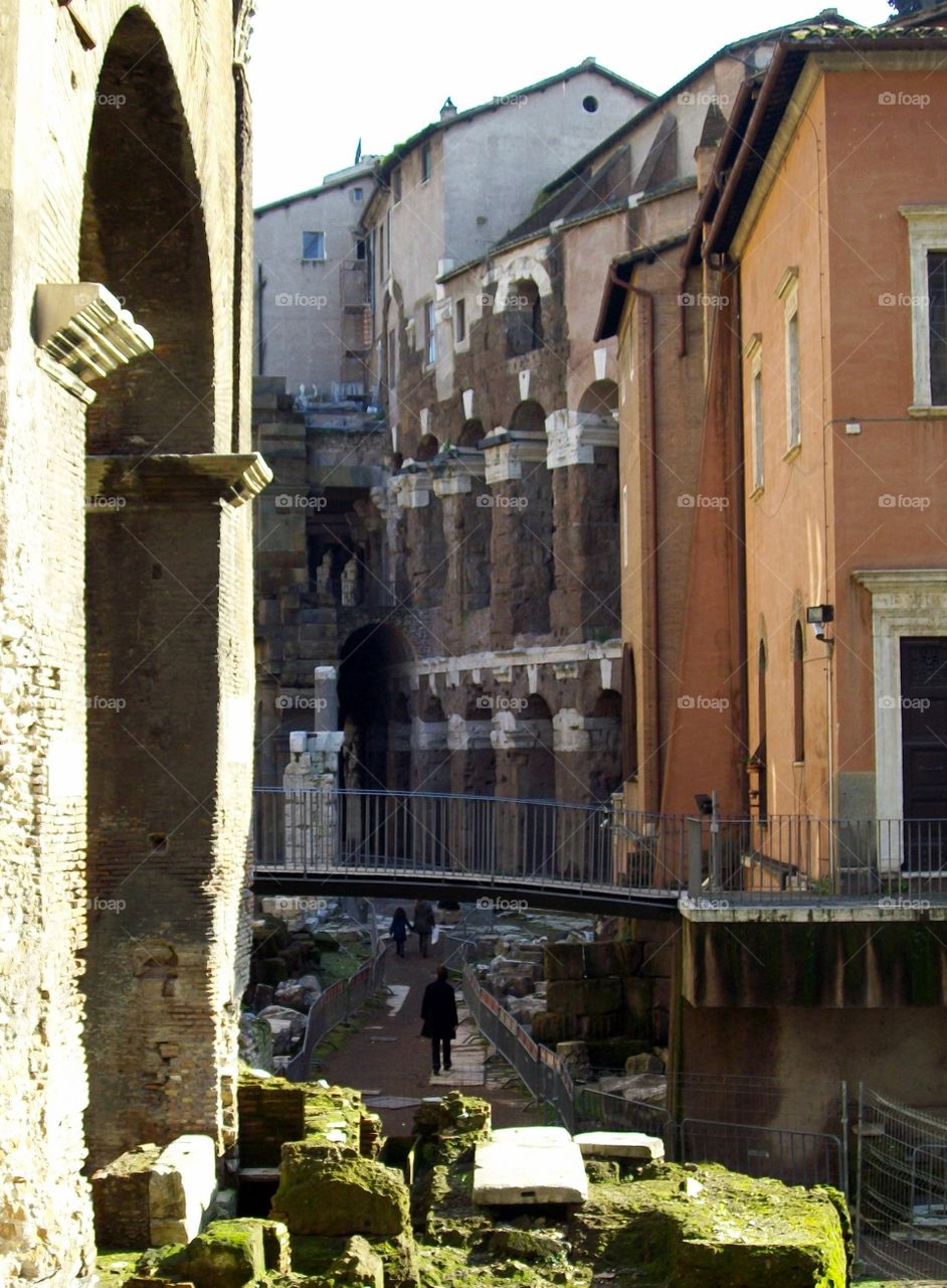 A pathway through Italian streets where people pass through new and old architecture  