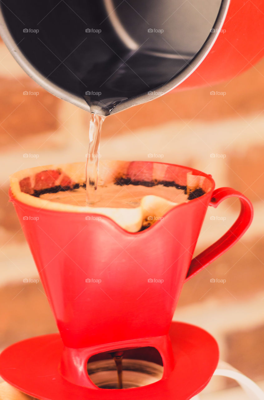 Pouring hot water in cup of ground coffee