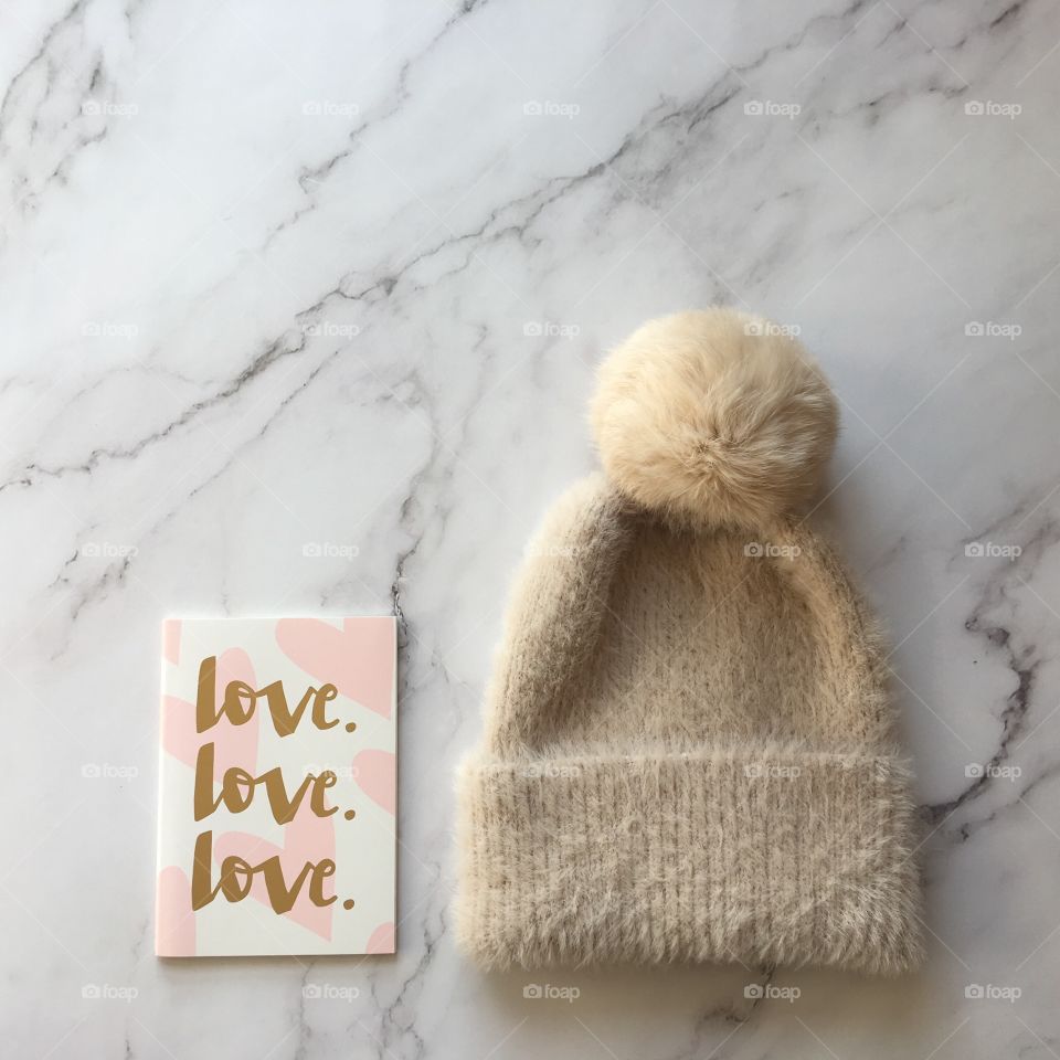 Flat lay items. Winter hat, card with inscription love lying on marble background 