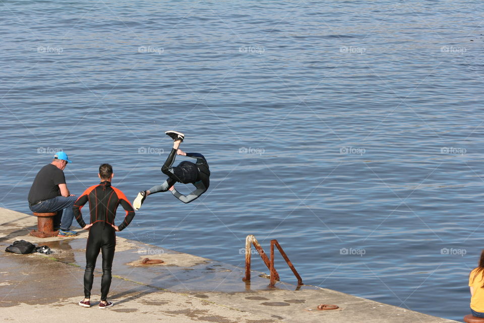 A person somersaulting into the harbour at Ballintoy