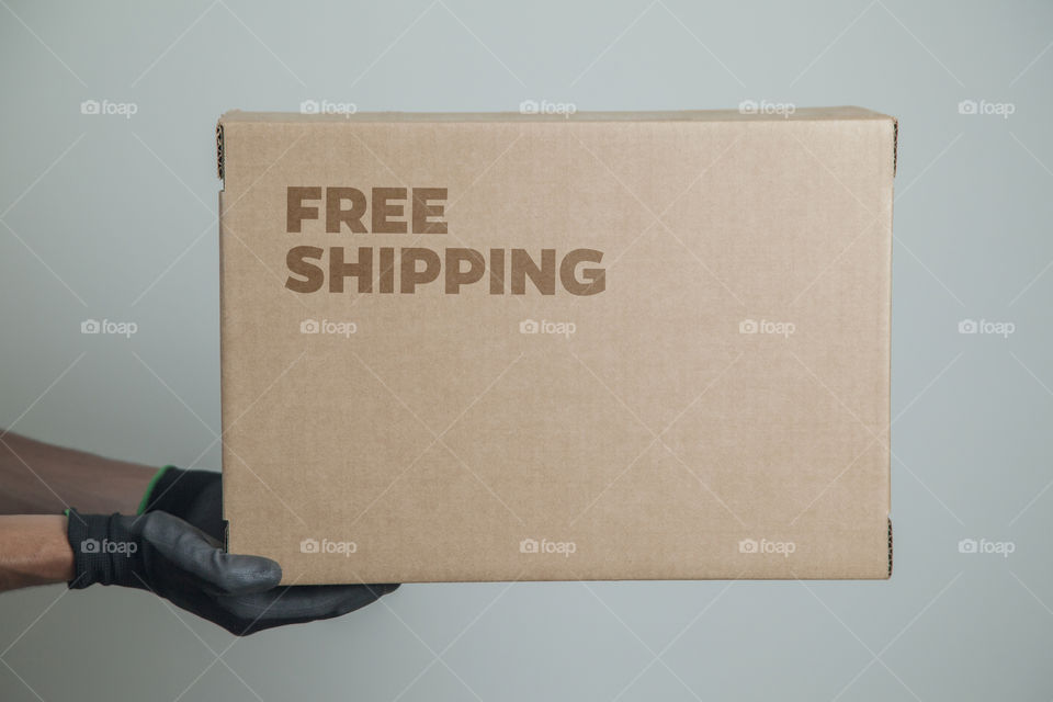 Cardboard box with written free shipping order placed on the floor in front of the house door at the time of delivery with the house door in the background. free delivery concept. transport concept.