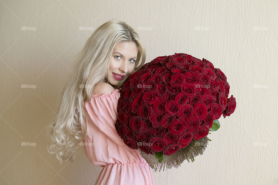 Happy young woman holding bouquet of red roses