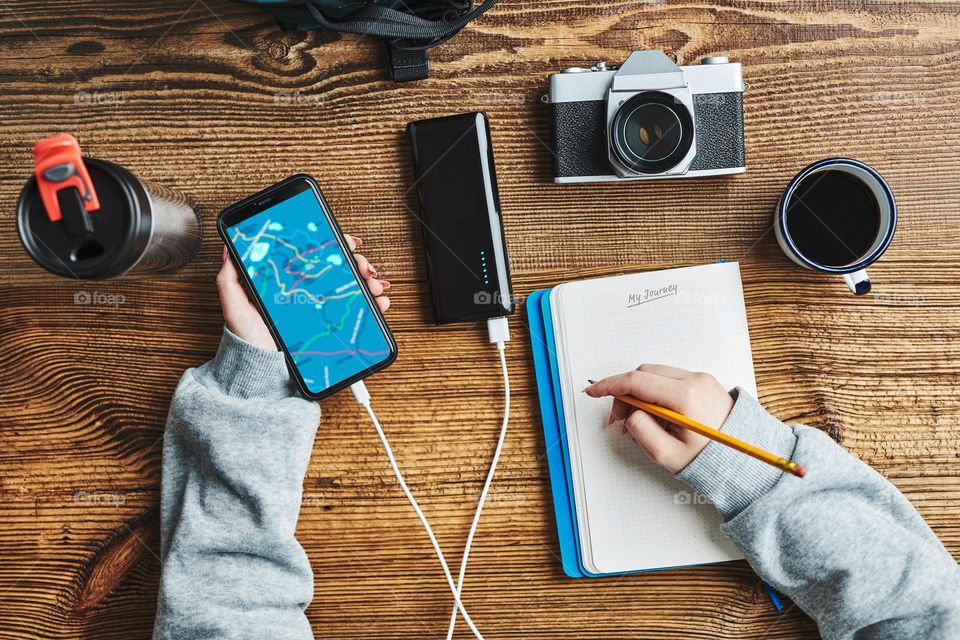 Woman planning next vacation trip while journey. Girl searching travel destination and routes using navigation map on mobile phone. Charging smartphone with power bank. Using technology while travelling