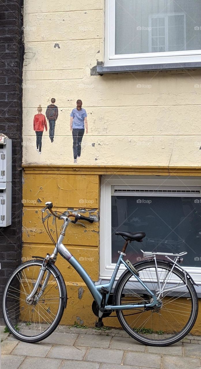city bike placed against a wall featuring little poeple