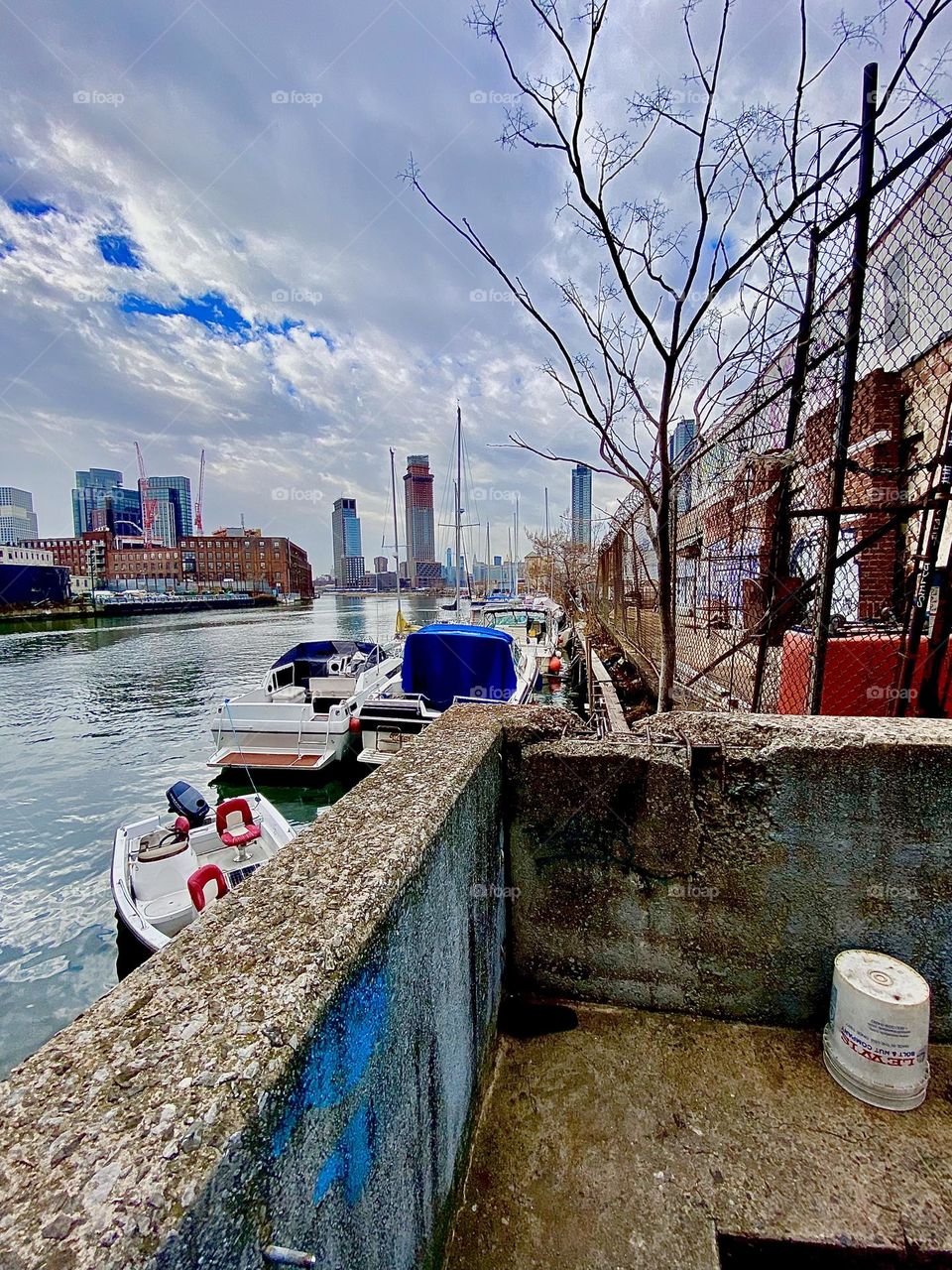 A cloudy day at Newtown Creek in Long Island City, Queens, NY overlooking the East River with its boats and in the distance Greenpoint, Bklyn is visible as well as parts of Manhattan. 2021. Hypnotic Productions