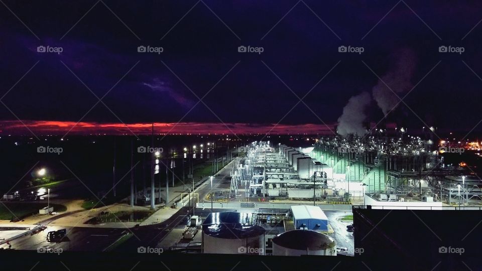 Beautiful Sunrise over natural gas power plant. vivid pink, red and blue sky with led street lights.