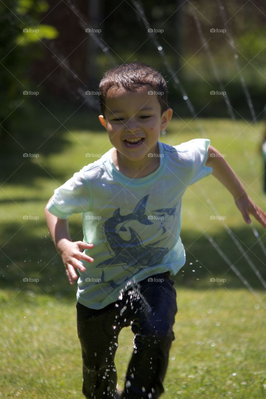 Boy running through the sprinkler 