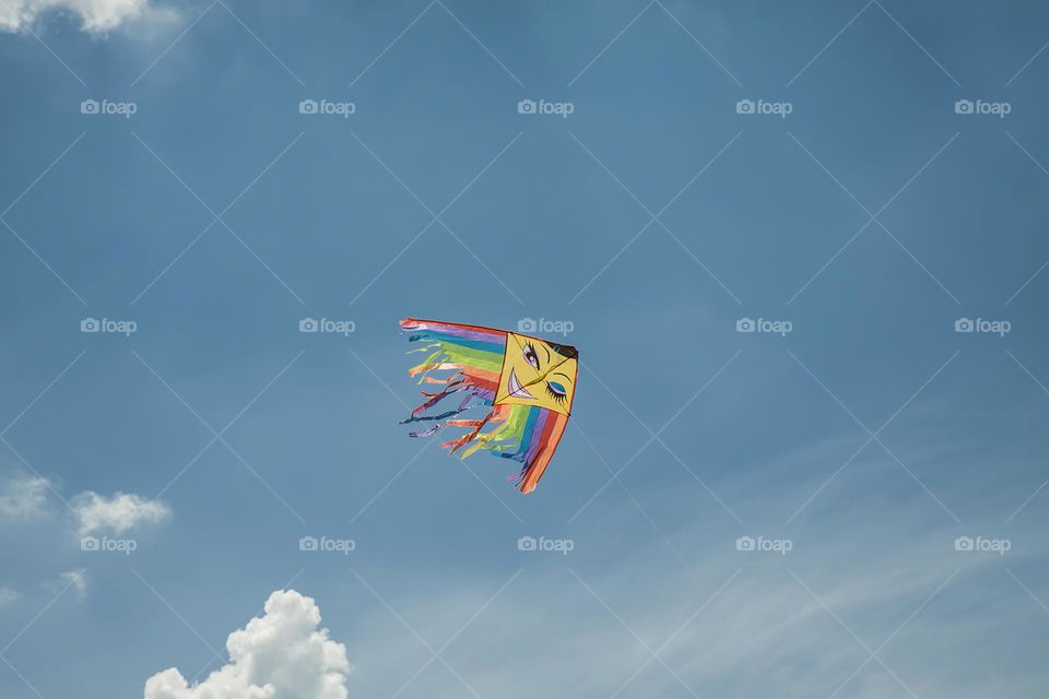 A rainbow-colored kite soars high in the sky, its vibrant hues representing LGBT colors