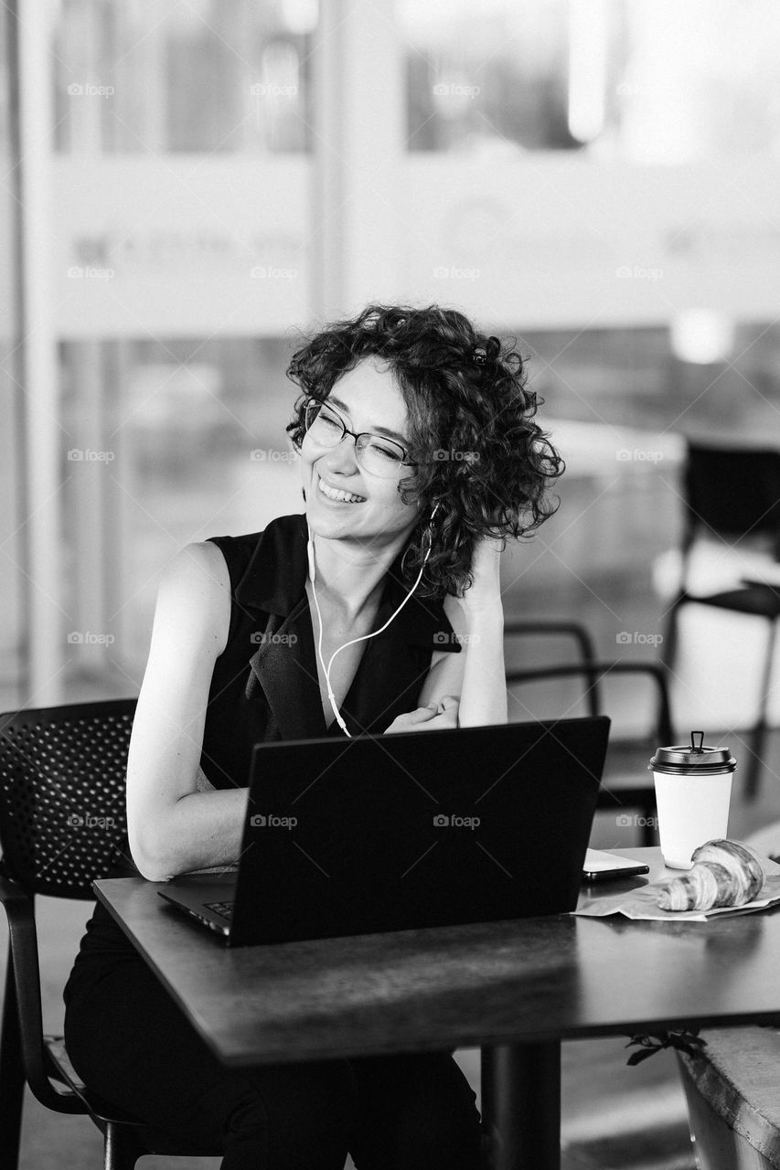 Black and white portrait of smiling woman in glasses. Candid emotions