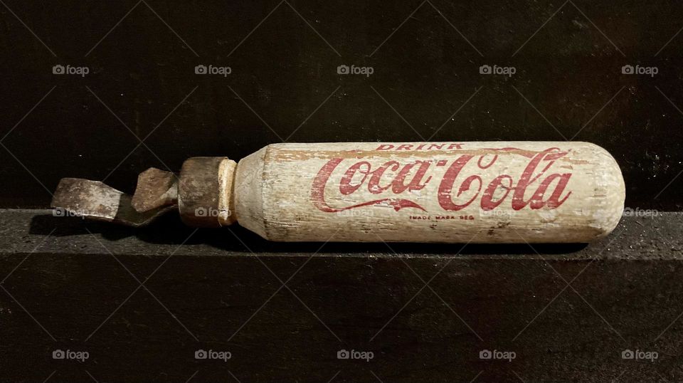 Antique Coca-Cola bottle opener on brown.