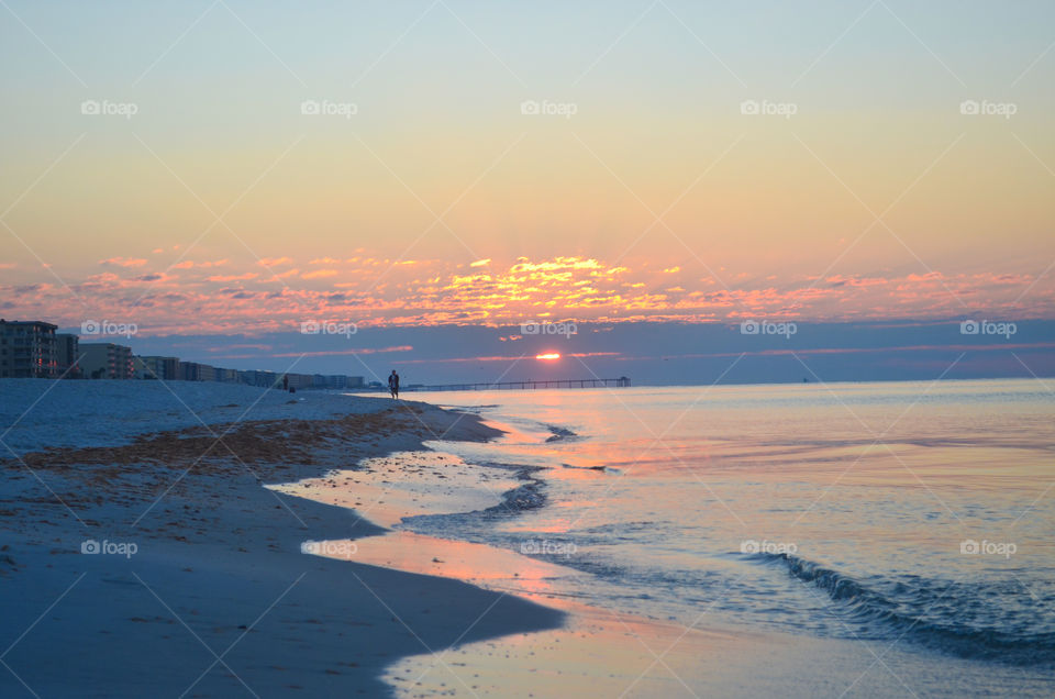 A person walking on the beach during the sun rise