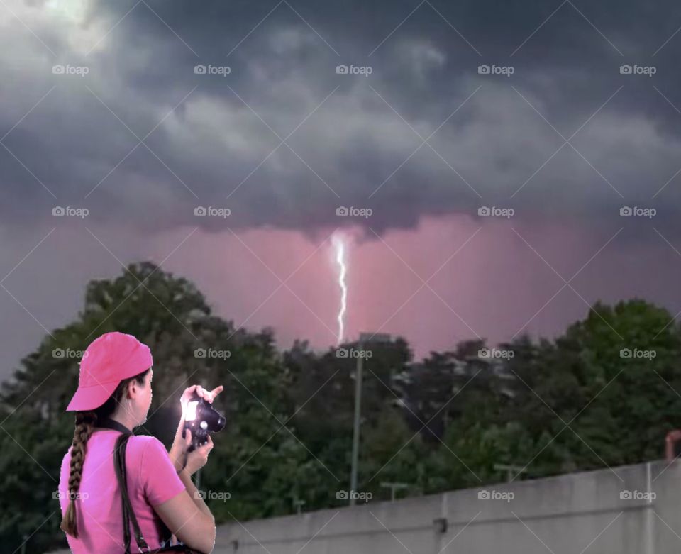 A photographer takes a picture of a lightning bolt strike during a thunderstorm 