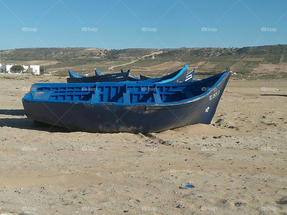 Alone blue boat on a sand.