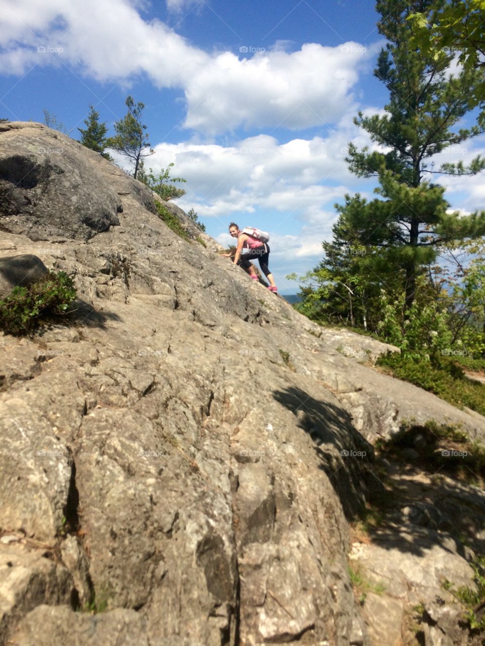 Woman with backpack climbing on rocky mountain