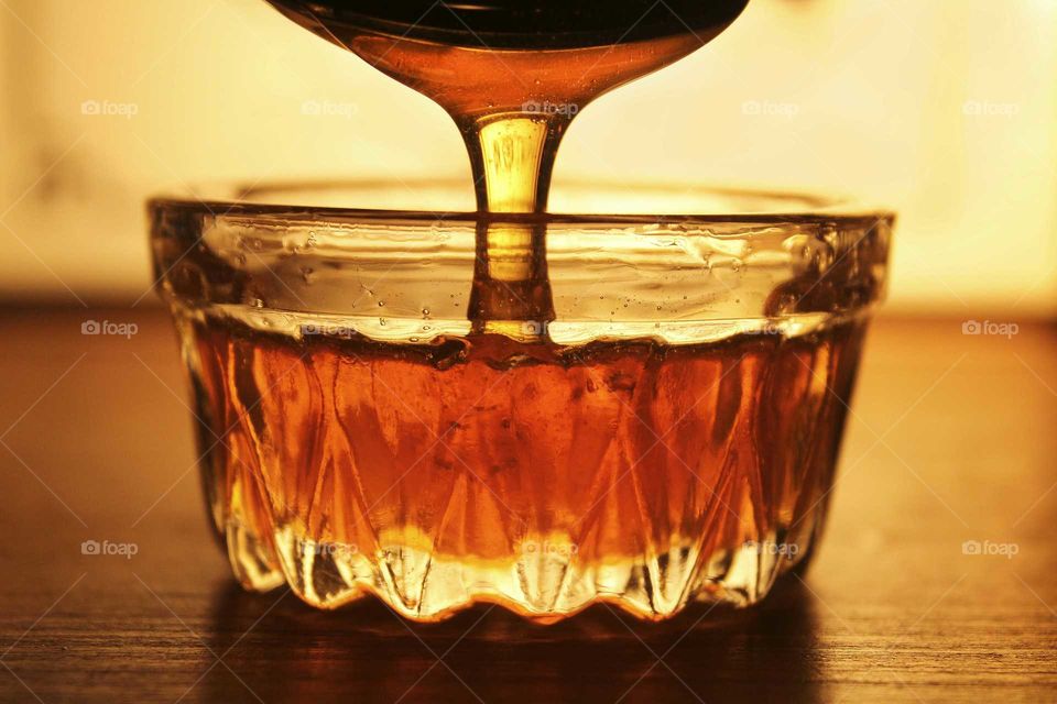 Honey pouring into a glass bowl