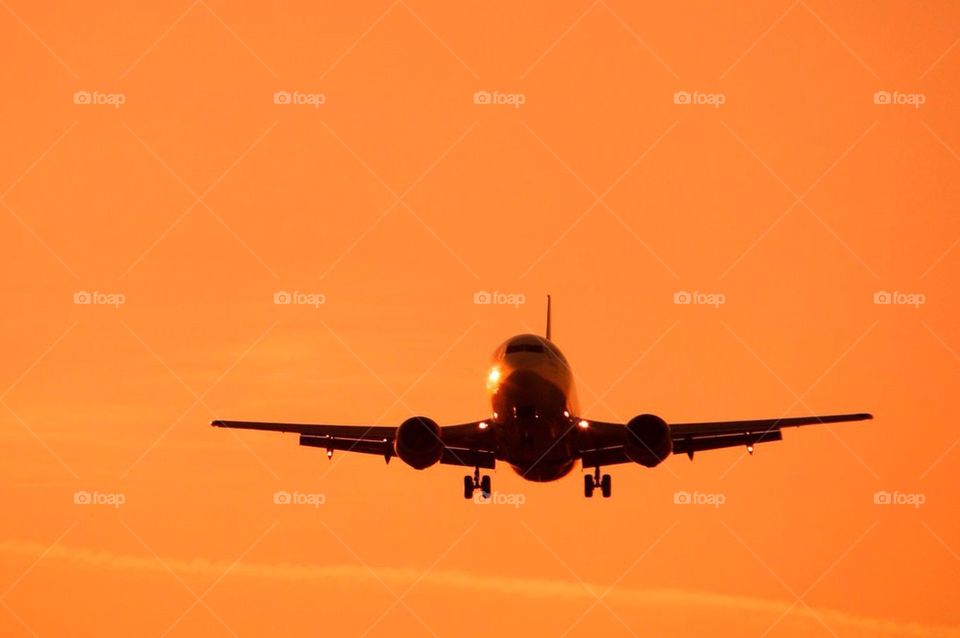 Plane coming in to land in sunset sky