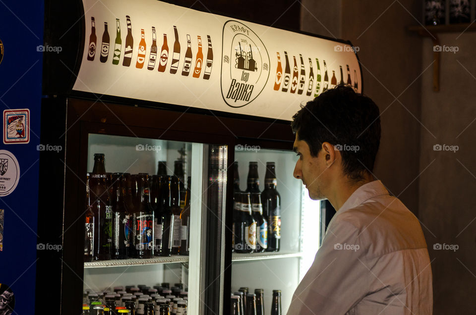Man in a dark bar choosing bottle of beer
