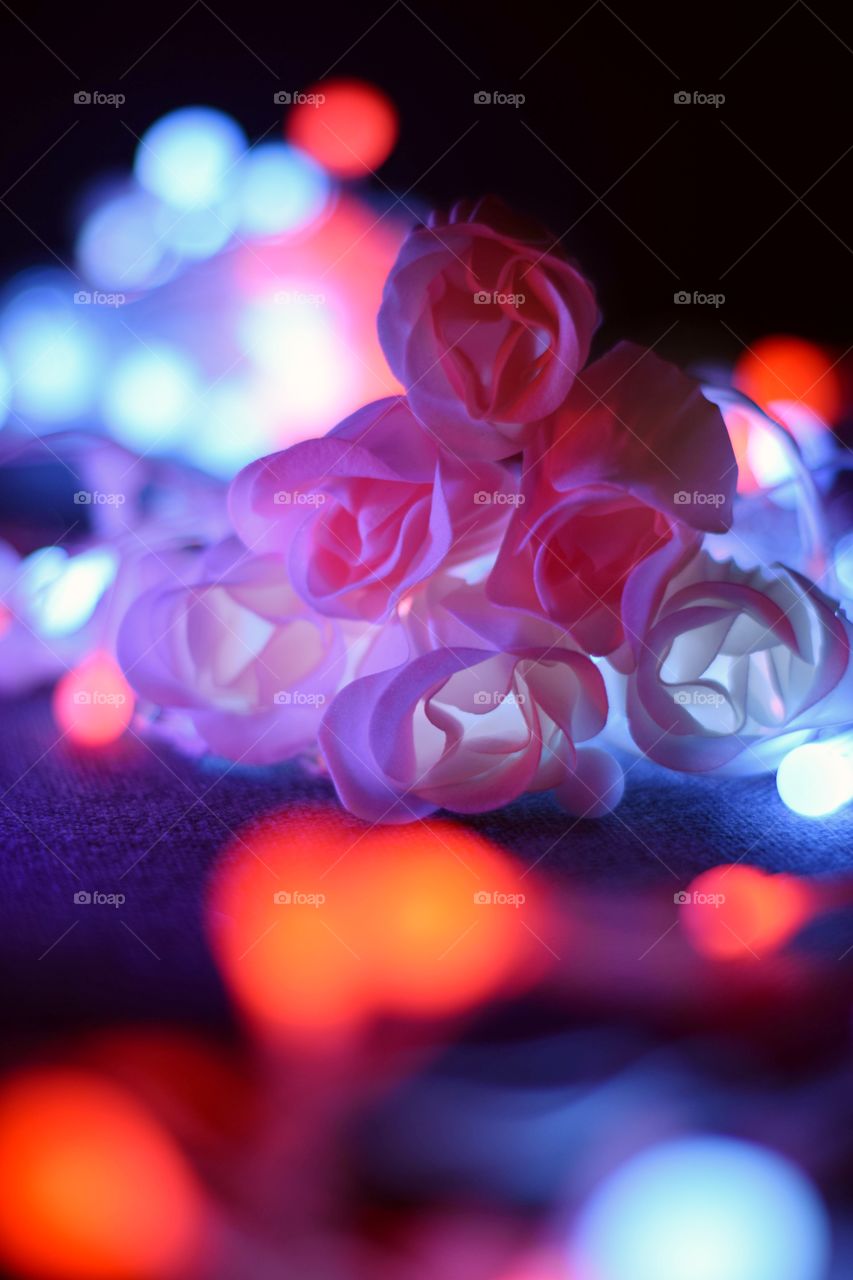 A bouquet of glowing roses. Multicolored bokeh and Led candles.
