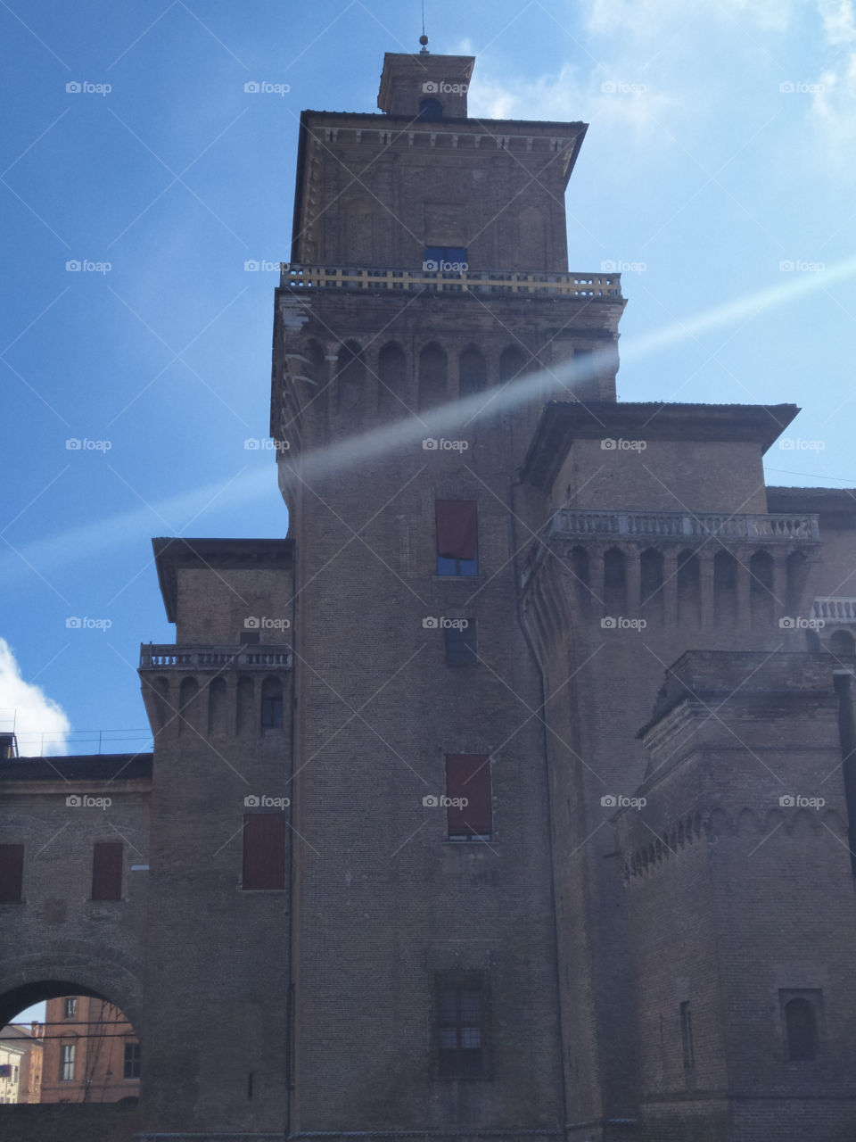 Ferrara.  One of the towers "Castello Estense", in front of which two rays of sunlight are visible