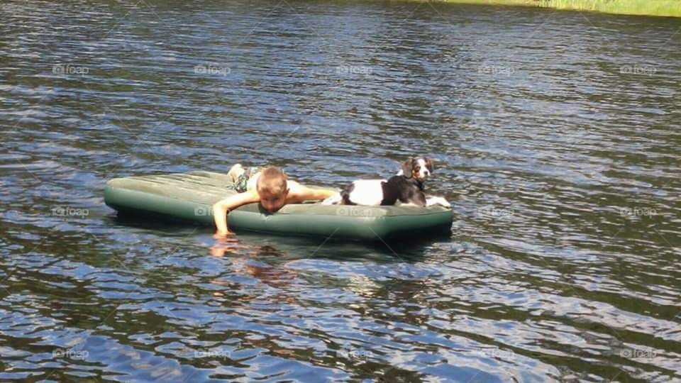 Boy and his dog on a lazy summer day float on a lake.