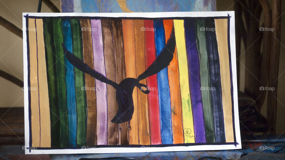 Black crow flying among the attractive hue of colours.