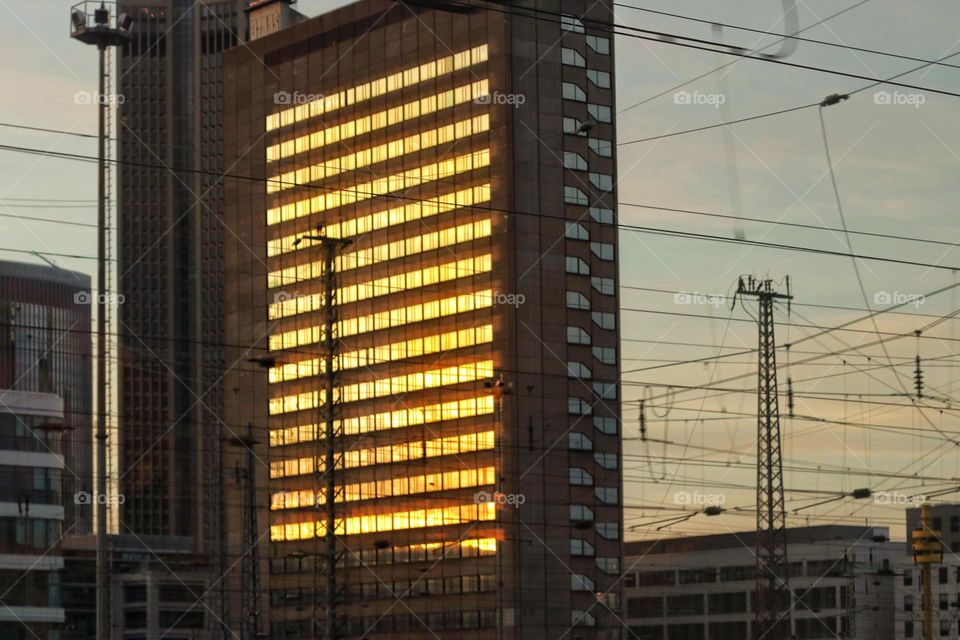 Skyscraper with a glass front at the train station reflecting the sunset