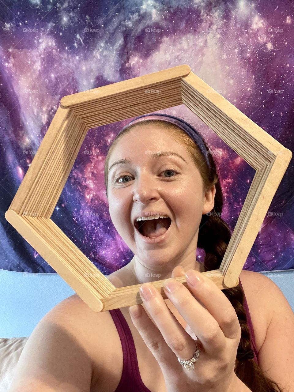 A young woman holding a homemade popsicle stick craft hexagonal shelf