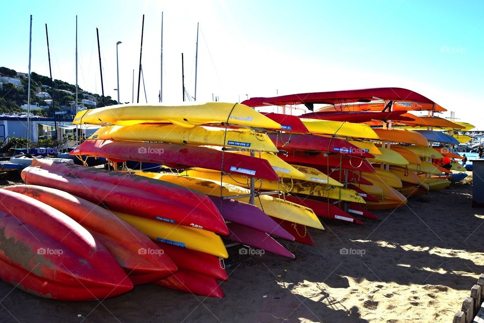 Red and yellow kayaks stacked up on the beach  