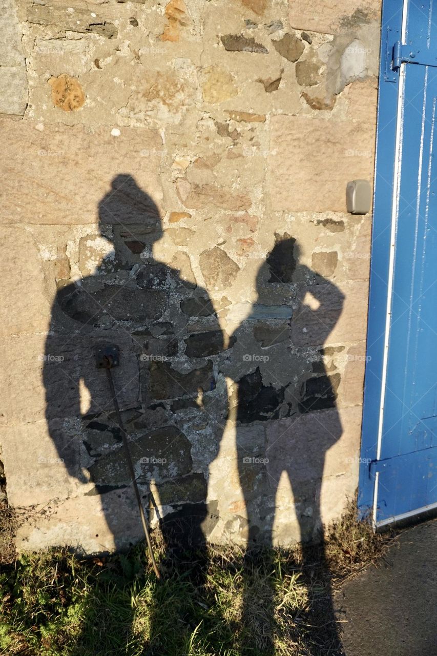 Me and my youngest son looking at our shadows on a stone building 