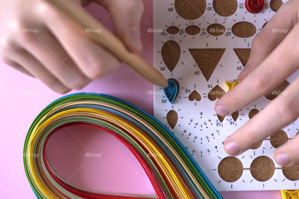 Hands doing quilling elements on a quilling board 