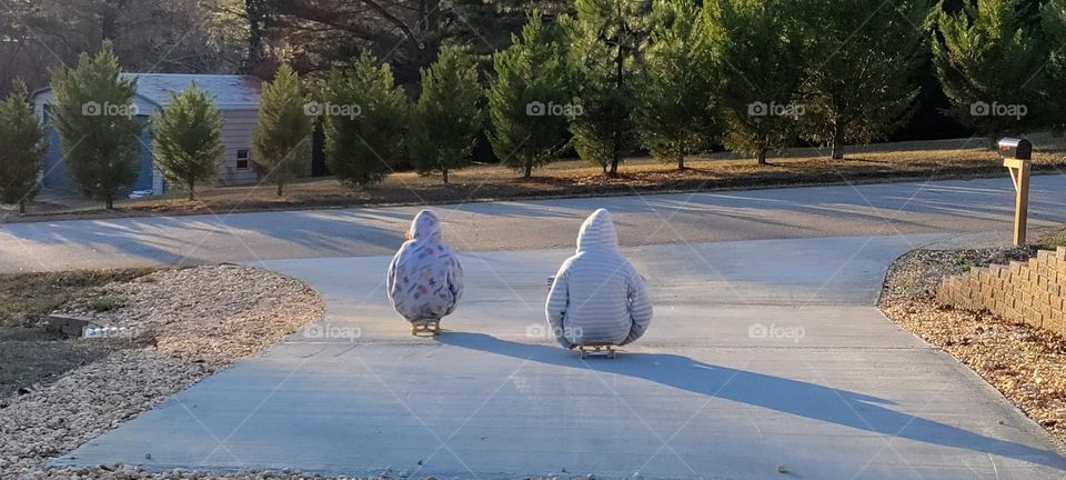 Two kids skateboarding in the cold weather