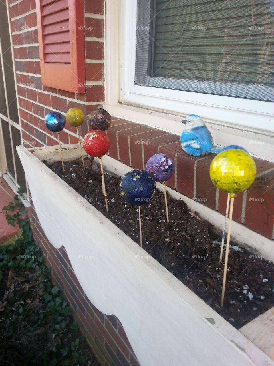 Painted ornaments on skewer wooden sticks on the window box. 