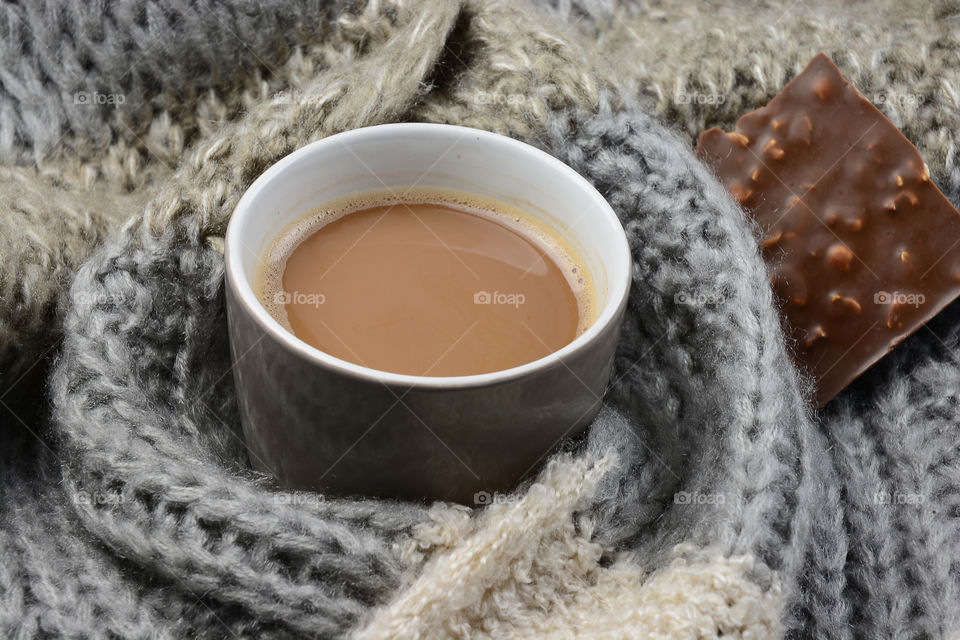 Cup of coffee with chocolate on blanket