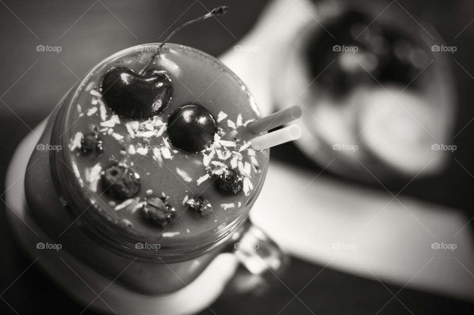 Black and white photography of fresh fruit smoothie with cherries coconut and oatmeal high angle view 