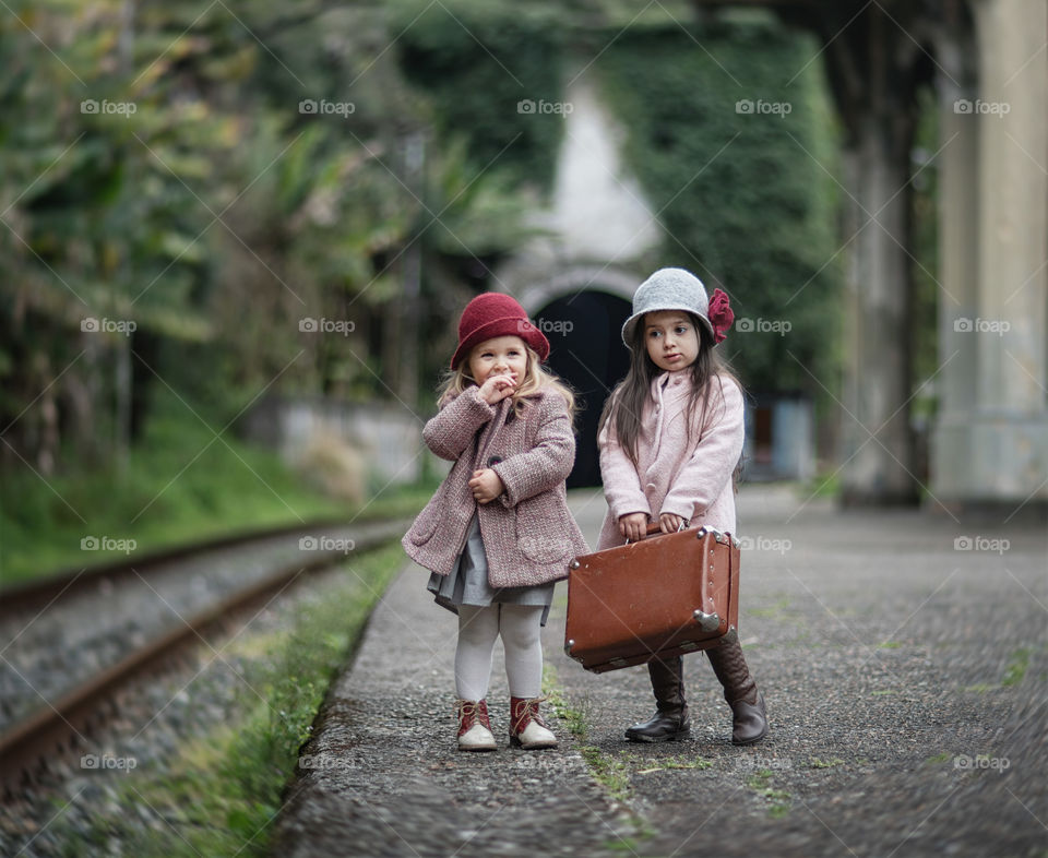 Little girls with suitcase are staying on a train station