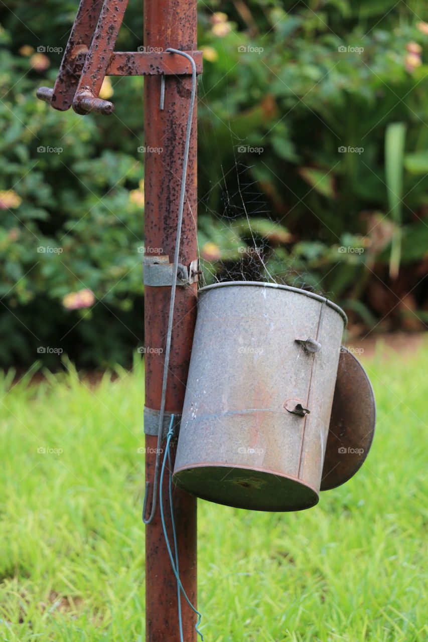 Old tin clothespin clothes peg can on iron pole in backyard