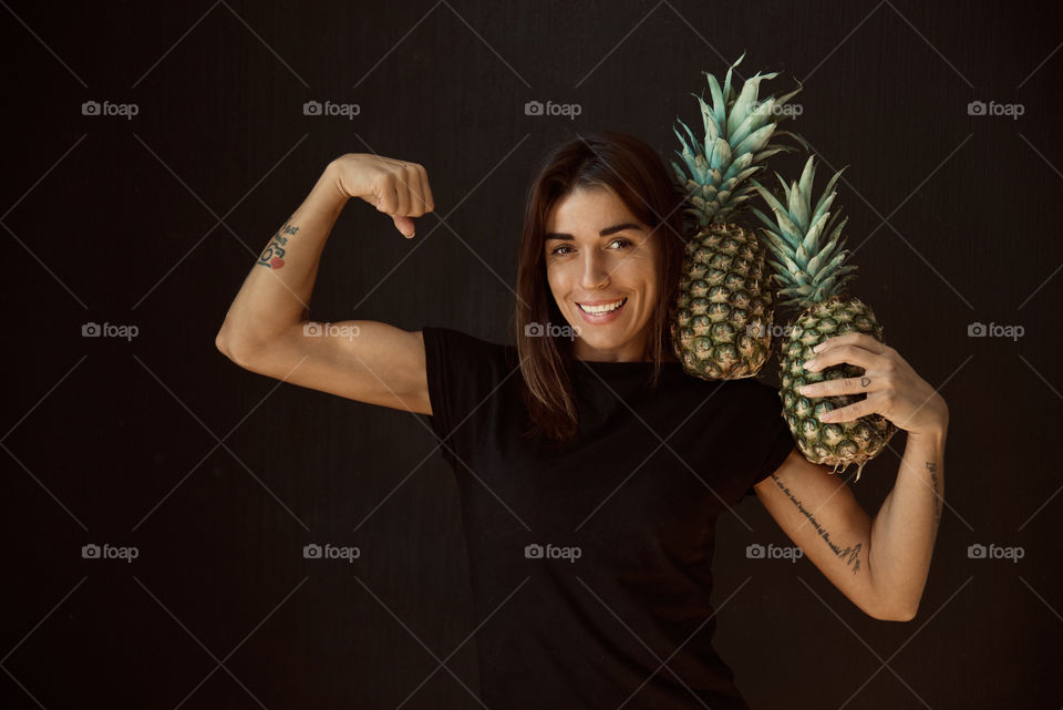 beautiful girl posing on camera with pineapple in her hands