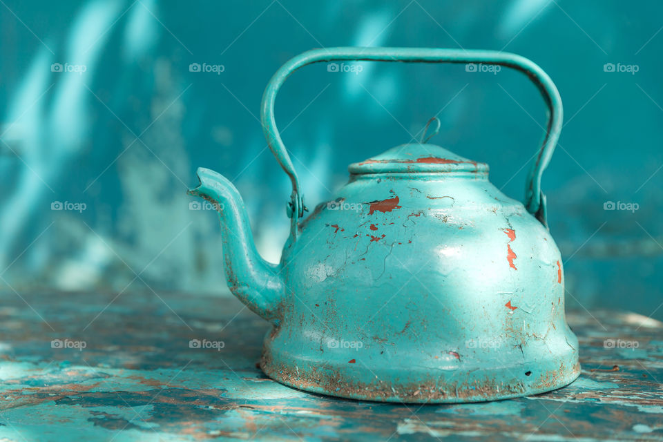 Old vintage turquoise teapot on the table