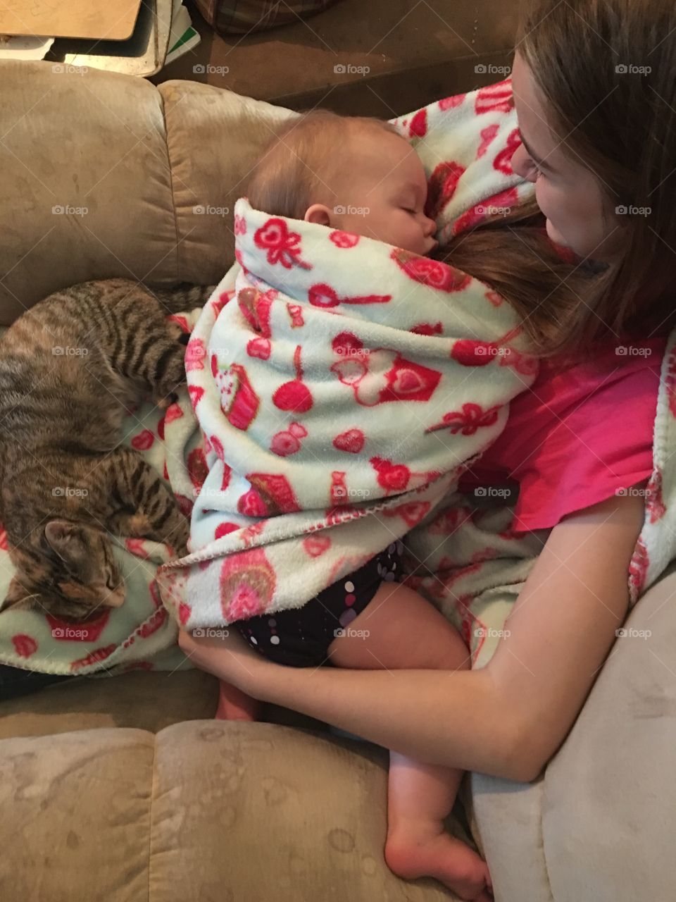 Elevated view of a girl carrying her sleeping brother with cat on sofa