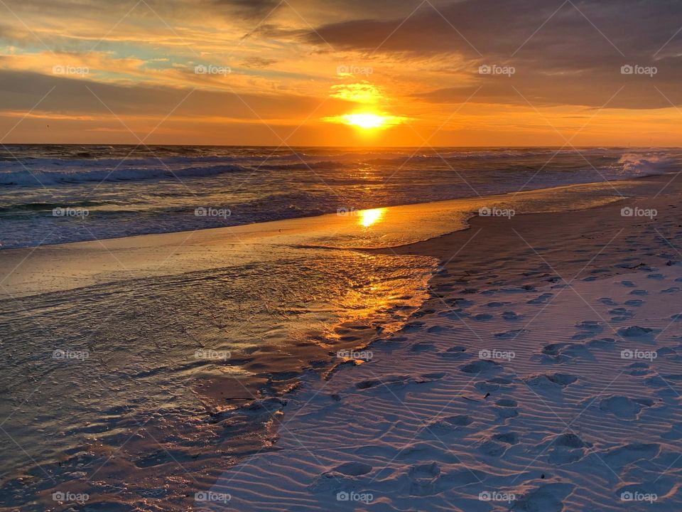 A Breathtaking descending sunset with picturesque peach colored Lenticular clouds over the Gulf of Mexico