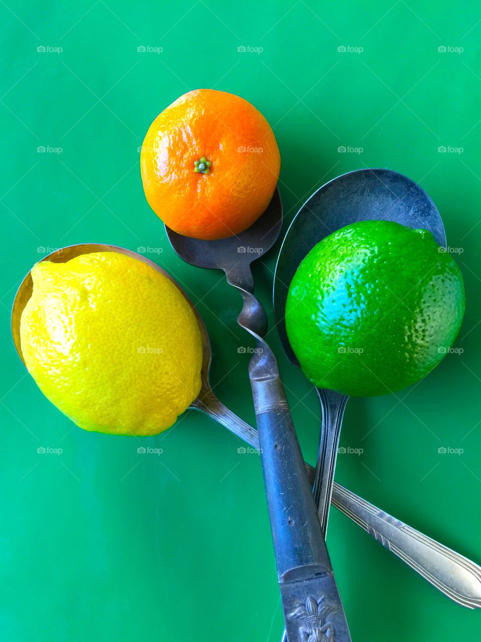 A clementine, lemon and lime on old spoons
