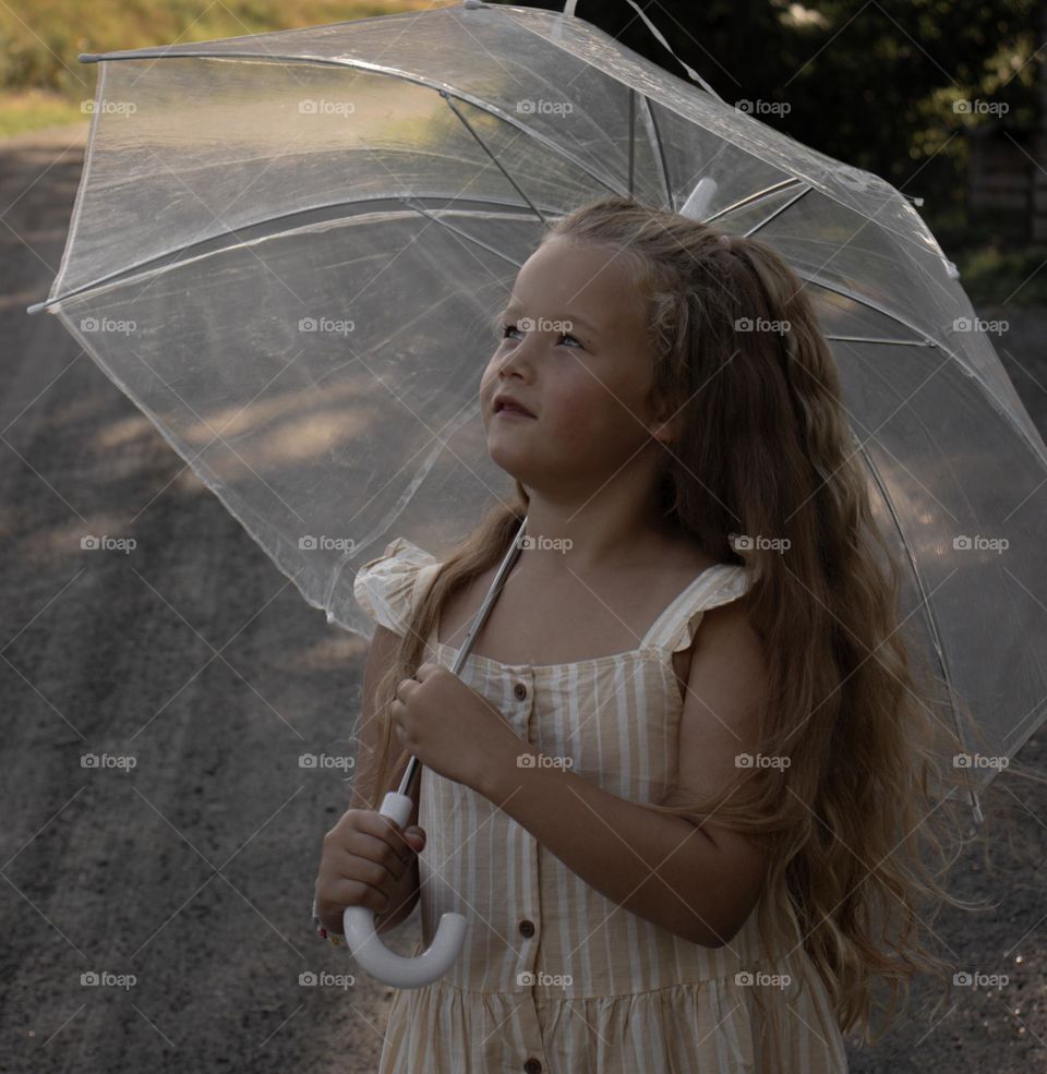 Little girl ,enjoy the sunny Day at the countryside, until the Rain Come.She runs for the umbrella and looked after the rainbow instead.