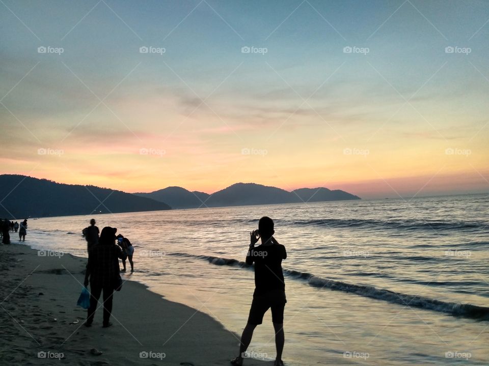 people taking photo during sunset at the beach