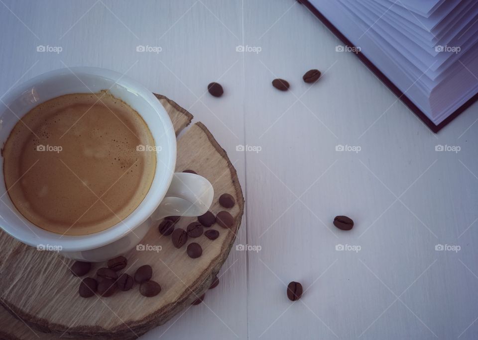Cup of coffee on the white wooden table with book 