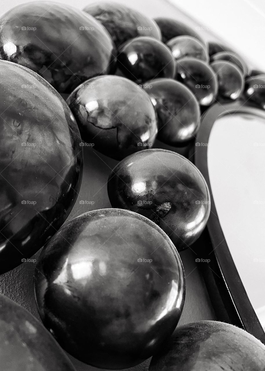 Round metal pebbles surrounding a mirror. Close up shot creating a textured image