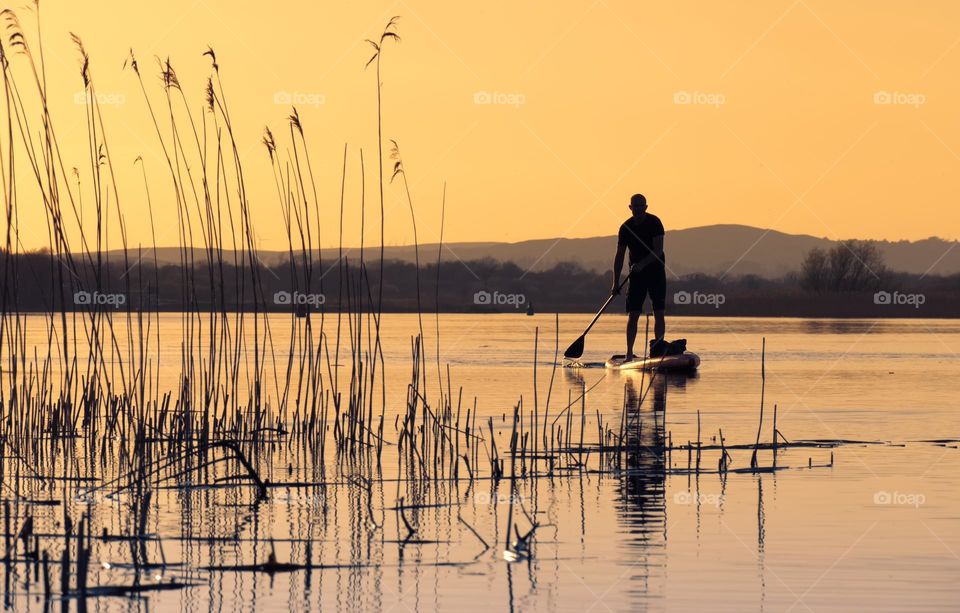 Stand up peddle boarder at sunset in Corrib river, Galway, Ireland