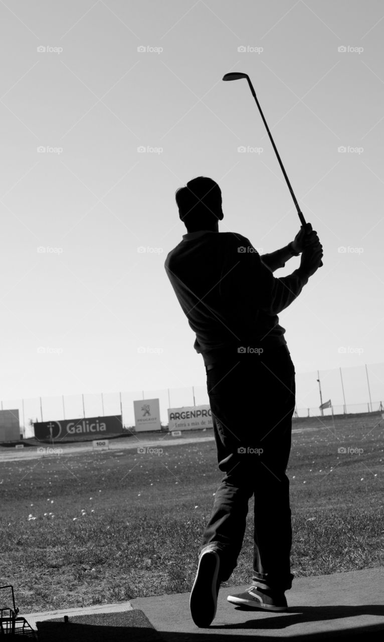 Silhouette of a man playing golf 