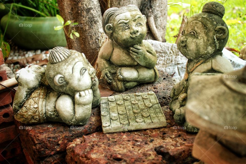 Stone figurines for garden decoration  Were placed in an orderly decorated manner, playing checkers in a lovely garden.