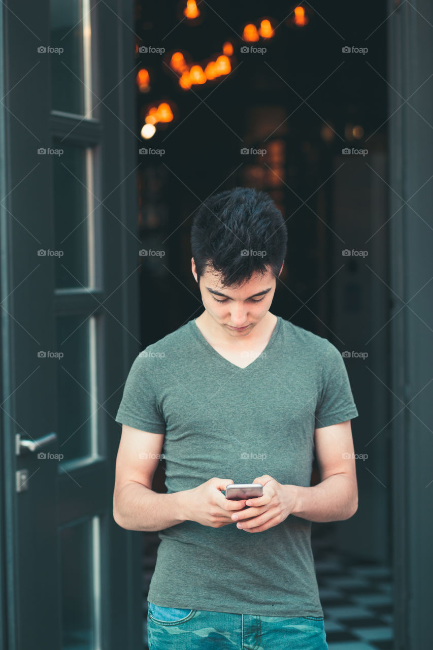 Young man using smartphone standing in center of town