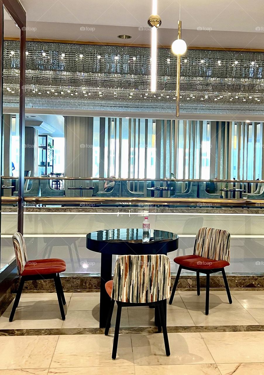 Black glossy table with three chairs in hotel lobby